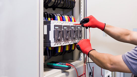 An electrical engineer checks the factory's electrical control cabinet.