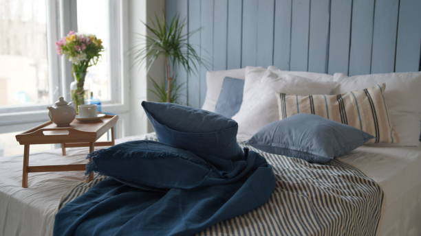 istock Large bed with pillows and blankets. Wooden stand for breakfast on crumpled bed in studio. Close-up of interior design room 1350118980
