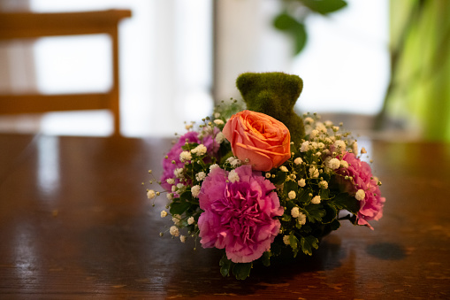 A green grass-made teddy bear with flowers from a banquet hall in Japan.