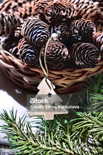 istock Wooden Christmas tree toy and wicker basket with cones. Christmas still life. Rustic style 1350134318