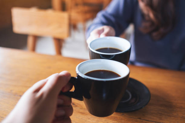 istock a man and a woman clinking coffee mugs in cafe 1350137731