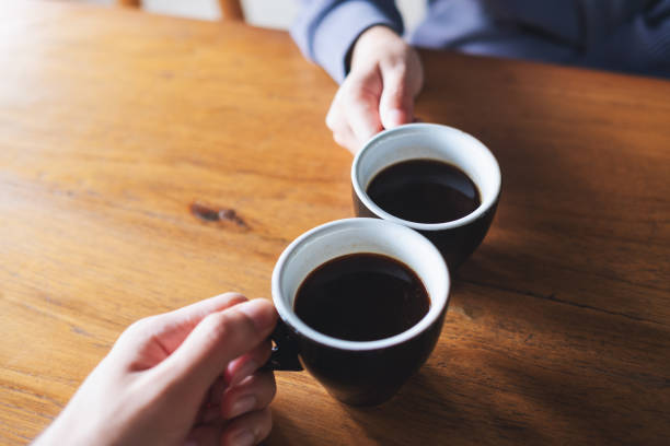 istock a man and a woman clinking coffee mugs in cafe 1350137735
