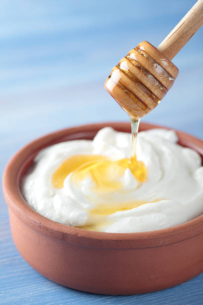 Bowl of Greek yogurt being topped with honey Greek yogurt with honey in a pot greek yogurt photos stock pictures, royalty-free photos & images
