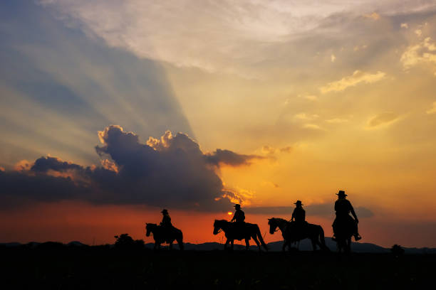Cowboy silhouette on horseback with mountain view and sunset sky. stock photo