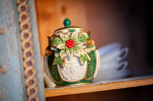 Porcelain canister with Christmas decorations inside an antique pantry.
