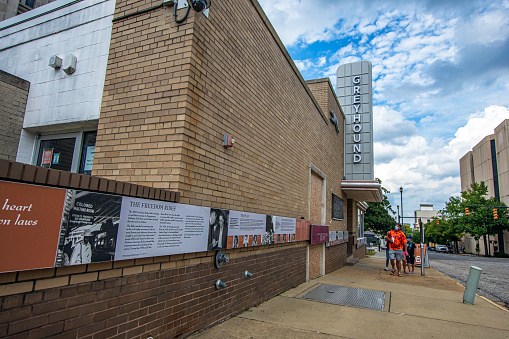 Montgomery, Alabama, USA - Oct. 2, 2021: Exterior of the Freedom Rides Museum in the old Greyhound bus station with a family wearing masks walking up the sidewalk looking at the information signs.
