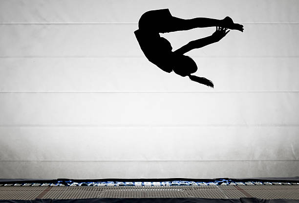 Silhouette of gymnast performing pike somersault stock photo