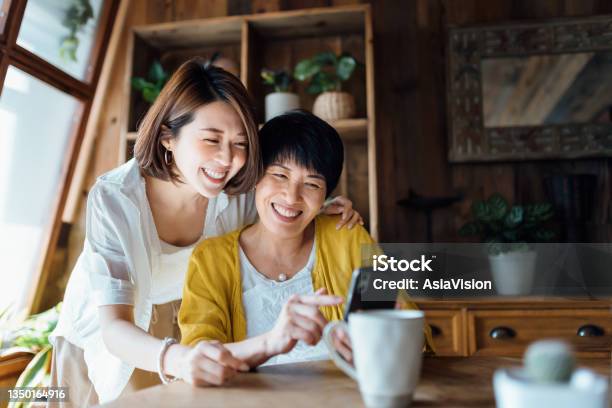 Affectionate Asian Senior Mother And Daughter Using Smartphone Together At Home Smiling Joyfully Enjoying Mother And Daughter Bonding Time Multigeneration Family And Technology Stock Photo - Download Image Now