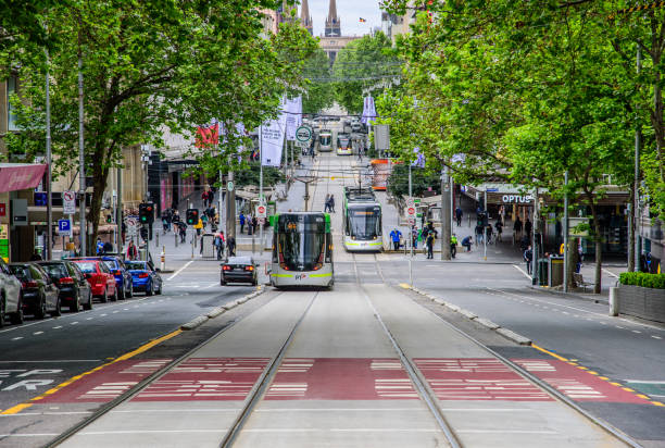A Public Transport Victoria tram is on Bourke Street while pedestrians cross the road stock photo