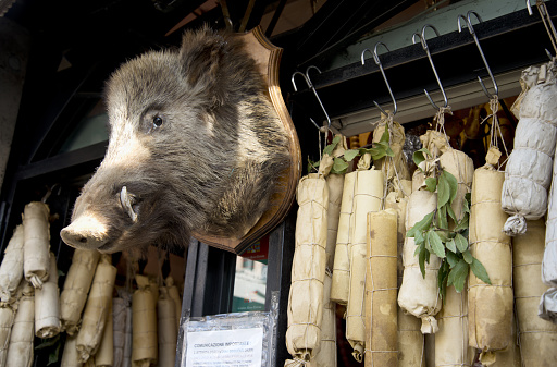 Rome, Italy: 10/28/2021. Wild boar head, sausages and salami hanging on hooks on a delicatessen store in Rome, Italy.