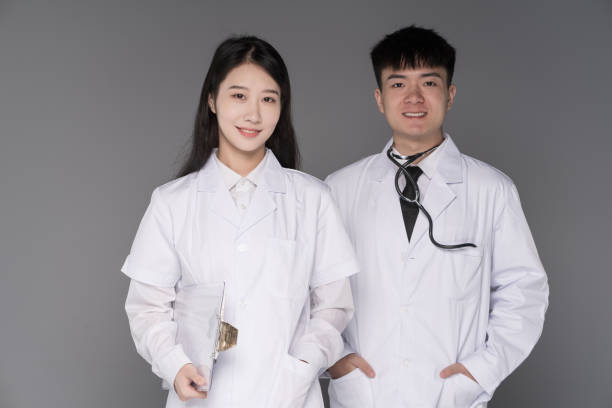 Two young Asian doctors, wearing white coats and smiling at the camera, are Korean cosmetic doctors stock photo