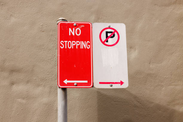White metal No Parking and red no stopping signs against a painted wall.