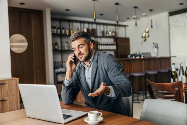 istock A businessman is sitting in the cafeteria and solving problems over the phone. There is a laptop on a table. A businessman and his remote business 1350171353