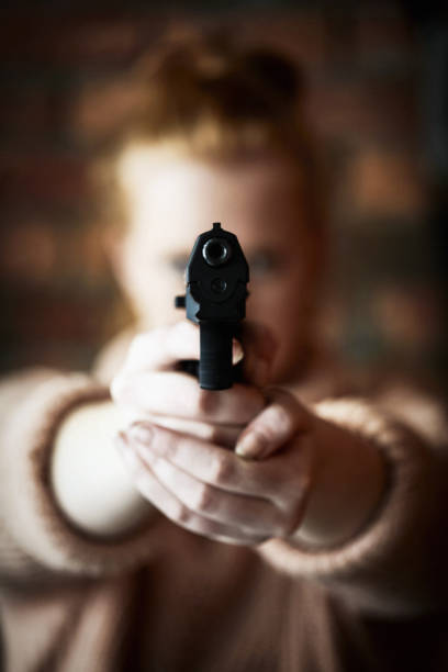 銃でカメラを狙う若い赤毛の女性 - gun women semi automatic pistol young women ストックフォトと画像