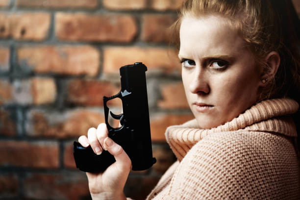 銃を持って見ている若い赤毛の女性 - gun women semi automatic pistol young women ストックフォトと画像