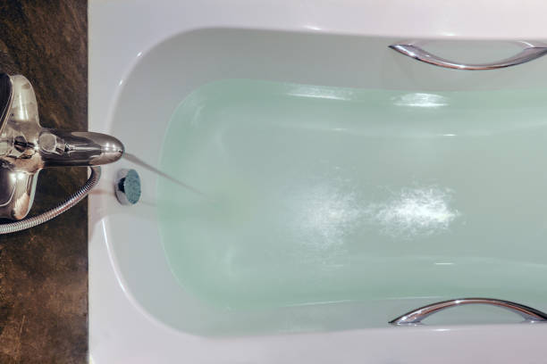 le bain blanc est rempli d’eau du robinet, en gros plan - cream coloured sink faucet home interior photos et images de collection