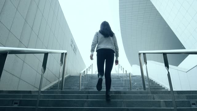 Young woman walking up stairs at a tunnel