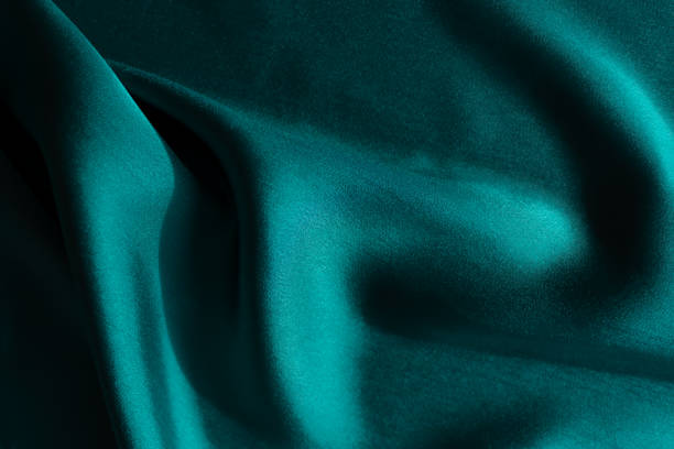 istock Blue-green satin fabric. Smooth silk fabric cut off on the table. 1350180739