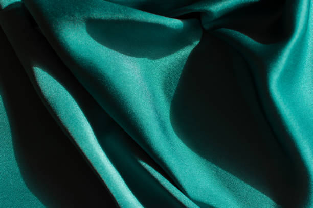 istock Blue-green satin fabric. Smooth silk fabric cut off on the table. 1350180800