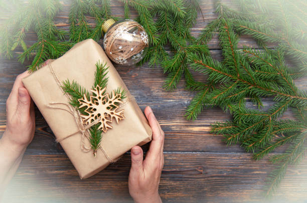 istock Old woman hands with christmas present and christmas branches 1350183775