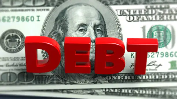 Red-colored debt text and American hundred dollar bill. On grayish blue-colored background. Horizontal composition with copy space. Focused image.