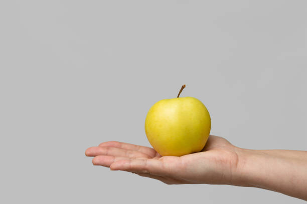 istock A small yellow apple lies in a woman's palm. 1350191577