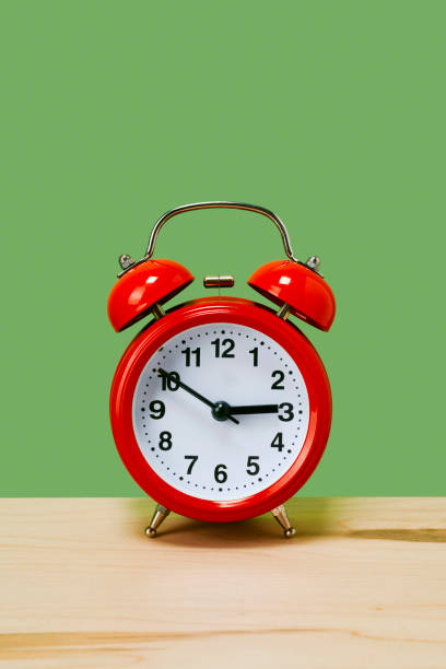 istock traditional red alarm clock on a green background 1350194433