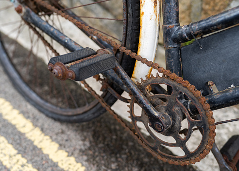 Rusty old bicycle chain in need of oil and maintenance.  Left out to the weather rusted and not working anymore.