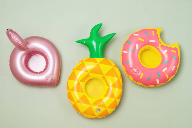 divers anneaux de jouets gonflables sur fond vert porte-boissons pour piscine party toy rings en forme de beignets ananas et flamant rose - toy umbrella photos et images de collection