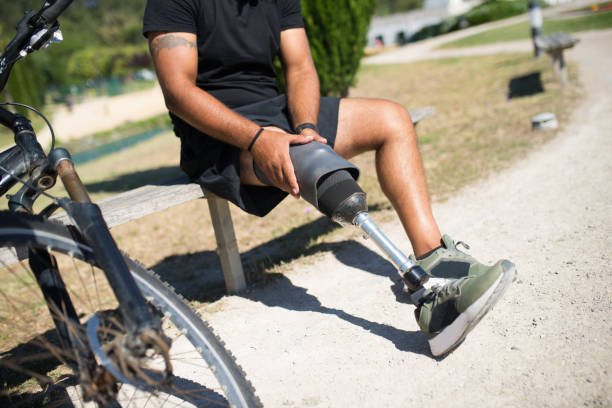 Close-up of man with disability getting ready for training. Man adjusting mechanical leg. Sport, disability concept