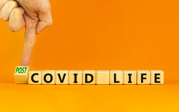 istock Symbol for a post-covid life. Businessman turns a cube and changes words 'covid life' to 'post-covid life'. Beautiful orange background. Medical, business and covid-19 pandemic concept, copy space. 1350200284