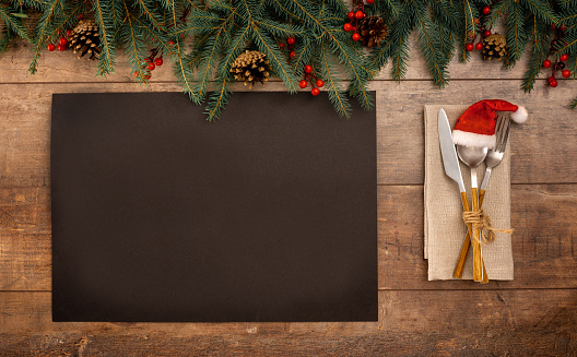 Christmas Recipe Menu. blank black paper on rustic wooden background. Christmas menu card. Christmas table place setting. Top view with copy space.