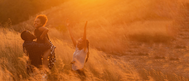 Soft focus. Happy African family father mother and child daughter travel and running on meadow nature on silhouette lights sunset.  Travel and Family Concept, copy space for banner