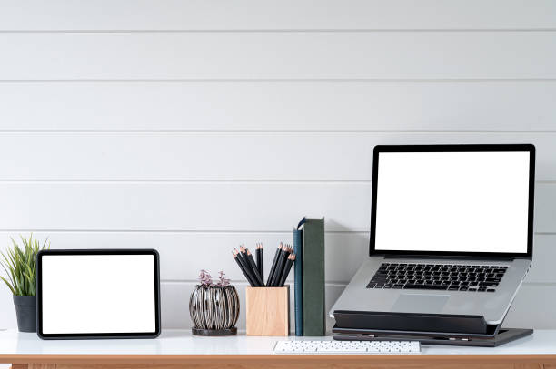 istock Blank screen tablet and laptop computer in minimal office room with decorations and copy space. 1350213127