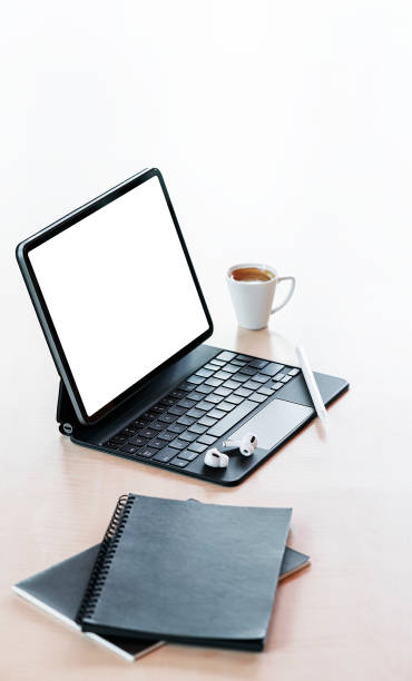 istock Blank screen tablet with magic keyboard, coffee cup and notebook on white background. 1350213383