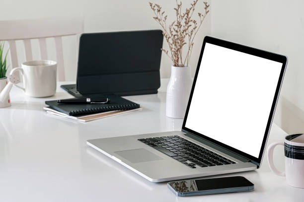 istock Mockup blank screen laptop computer and gadget on white top table in modern office room, 1350213399