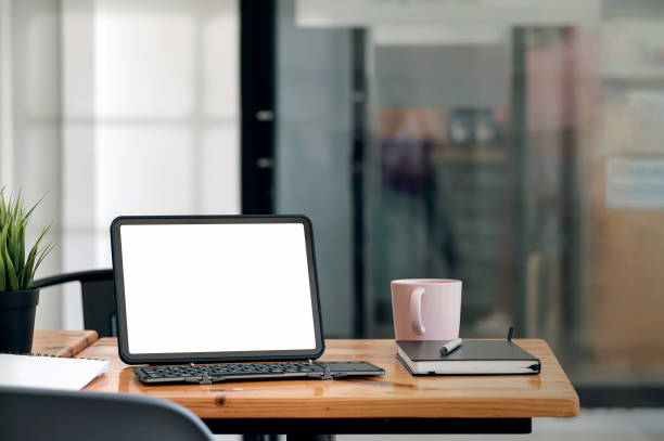 istock Creative workspace with blank screen tablet and keyboard on wooden table in office room. 1350213556