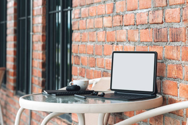 istock Blank screen tablet with magic keyboard and gadget on round table at cafe outdoors. 1350214999