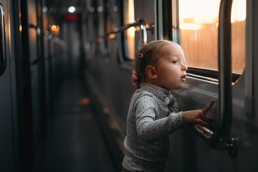 Girl, child looking though train window on sunset