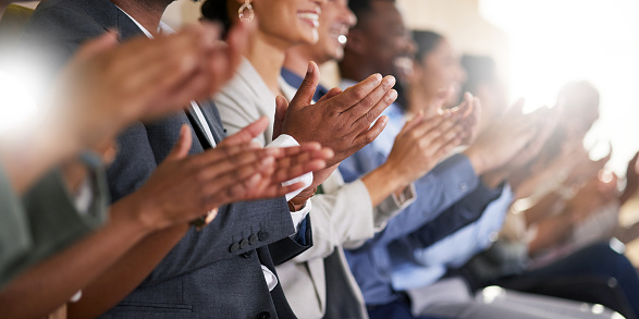 Foto recortada de un grupo indisgnible de empresarios aplaudiendo mientras están sentados en la sala de juntas durante una presentación. photo