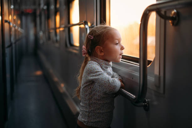istock Girl, child looking though train window on sunset 1350218415