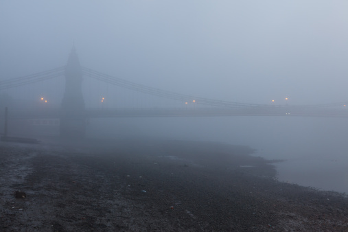 One side of Hammersmith Bridge in the fog with street lights barley visible