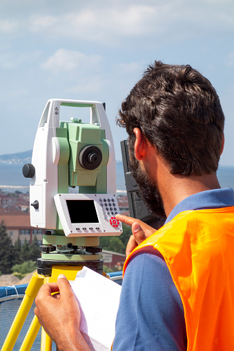 A male engineer works with the optical level on site