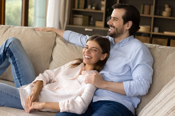 istock Happy millennial couple daydreaming, resting on couch. 1350227797