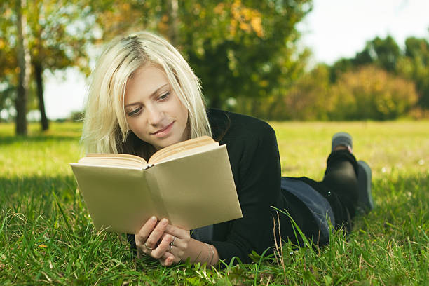 istock beautiful girl reading in park on grass 135023175