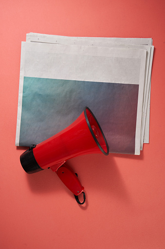 newspaper and megaphone on red background
