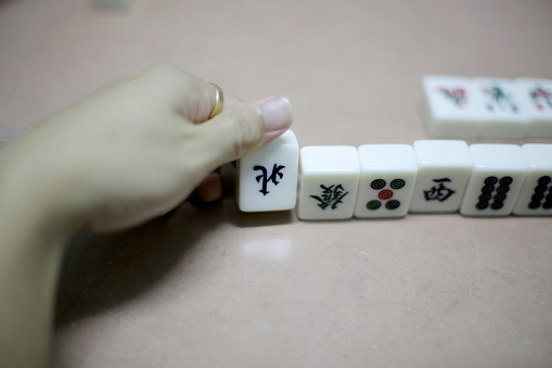 An Asian man is enjoying mahjong game at home.