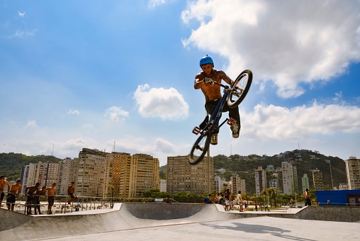 Santos, São Paulo, Brazil - March 8, 2009: BMX cyclist performing tricks in the air at the Emissário skate park. In the background, the waterfront buildings.