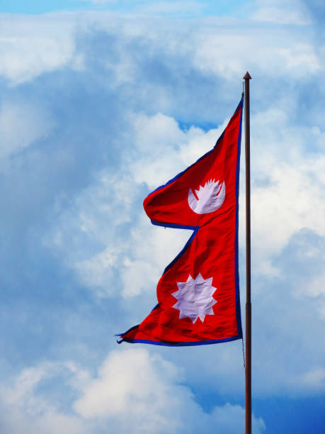 The flag of Nepal, The national flag of Nepal against the blue sky. Triangle Flag stock photo