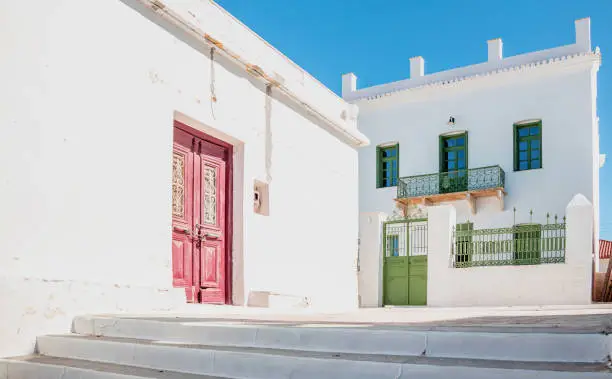 Cyclades typical architecture of one floor whitewashed houses empty stone stairs blue sky sunny day at Kythnos island, Chora village destination Greece. Summer vacation.